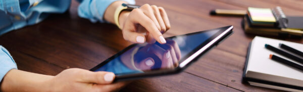 Woman pointing on digital tablet screen, chatting in social networks, meeting website, searching internet, sending sms, using text messenger or online banking. Close up of female hands holding device